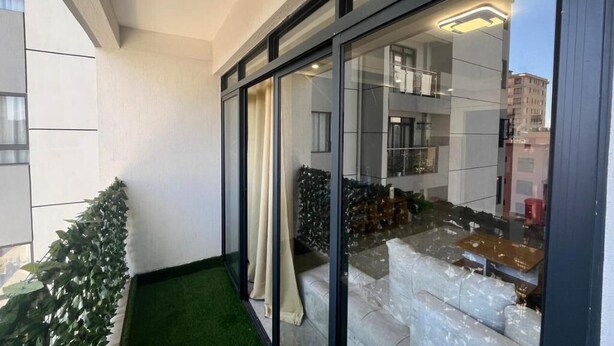 A modern apartment with a balcony, a glass door, and a view of the cityscape. - Nairobi Accomodation (Nairobi)