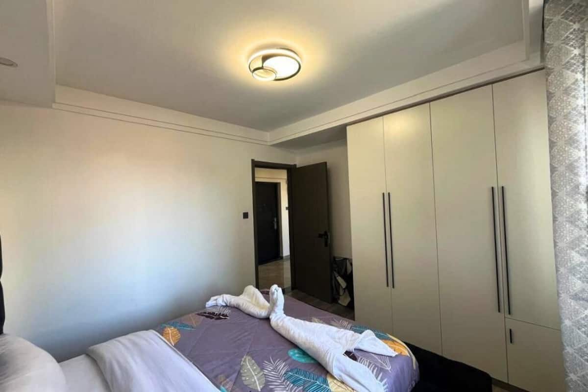 Une chambre d’hôtel avec un lit, une armoire et un luminaire au plafond.
