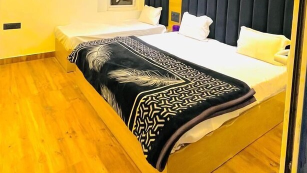 A modern bedroom with a bed, a ceiling fan, and a window. - Priya Kunj Dham (Mathura)