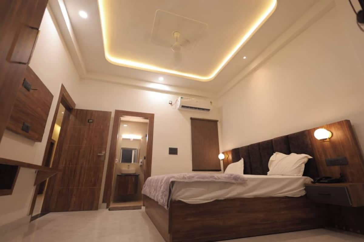 A modern bedroom with a wooden bed, bedside lamps, and a ceiling light fixture.