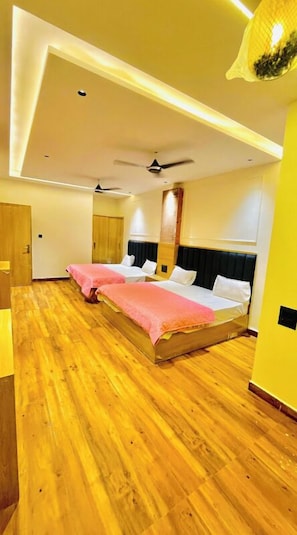 Habitación de hotel con dos camas, suelo de madera, ventilador de techo y diseño moderno.