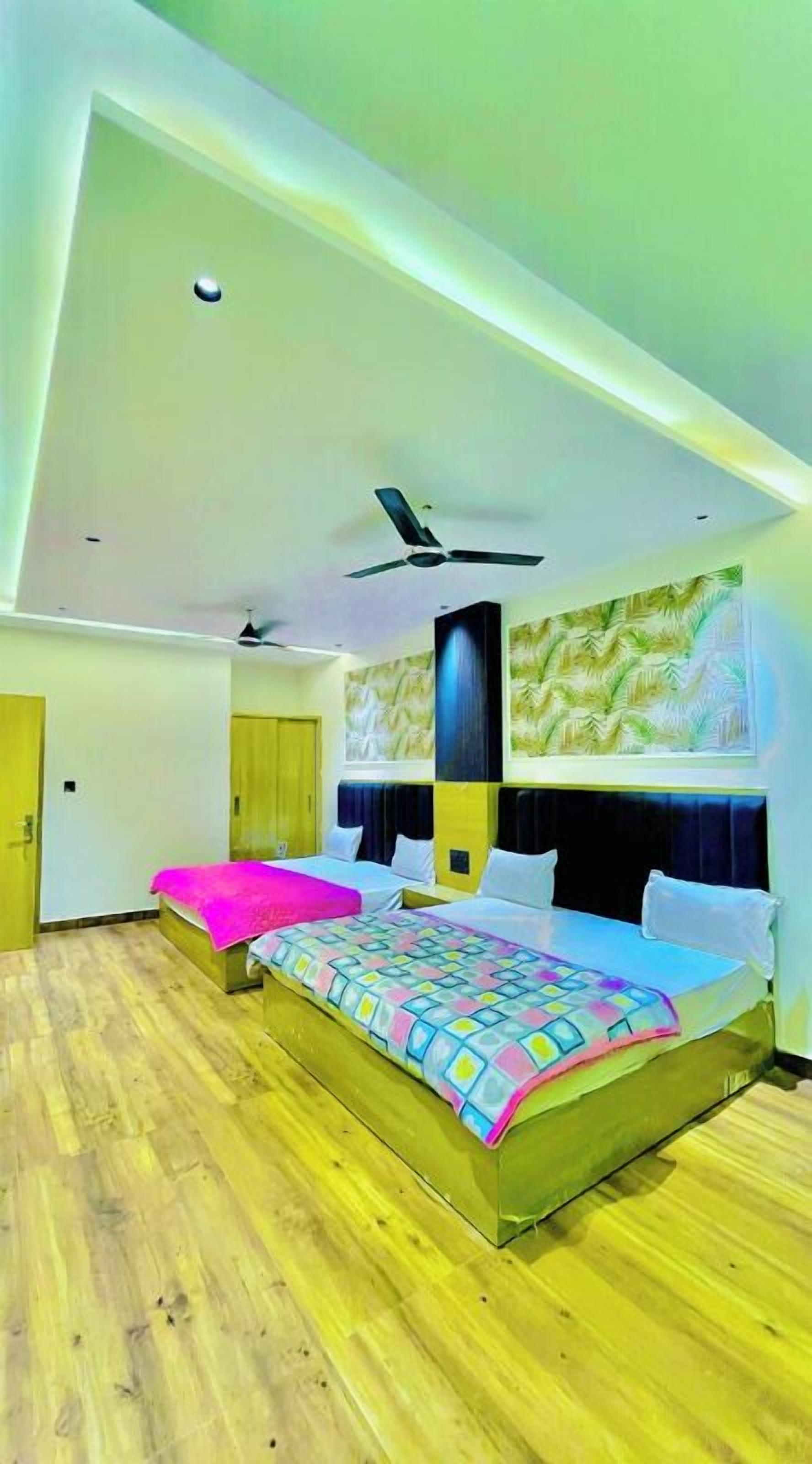 A modern hotel room with a large bed, a ceiling fan, and a painting on the wall.