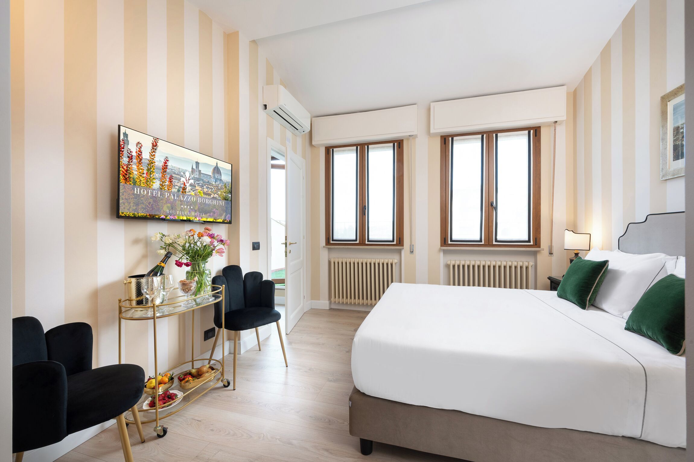 A hotel room with a bed, a desk with a chair, a window, and a radiator.