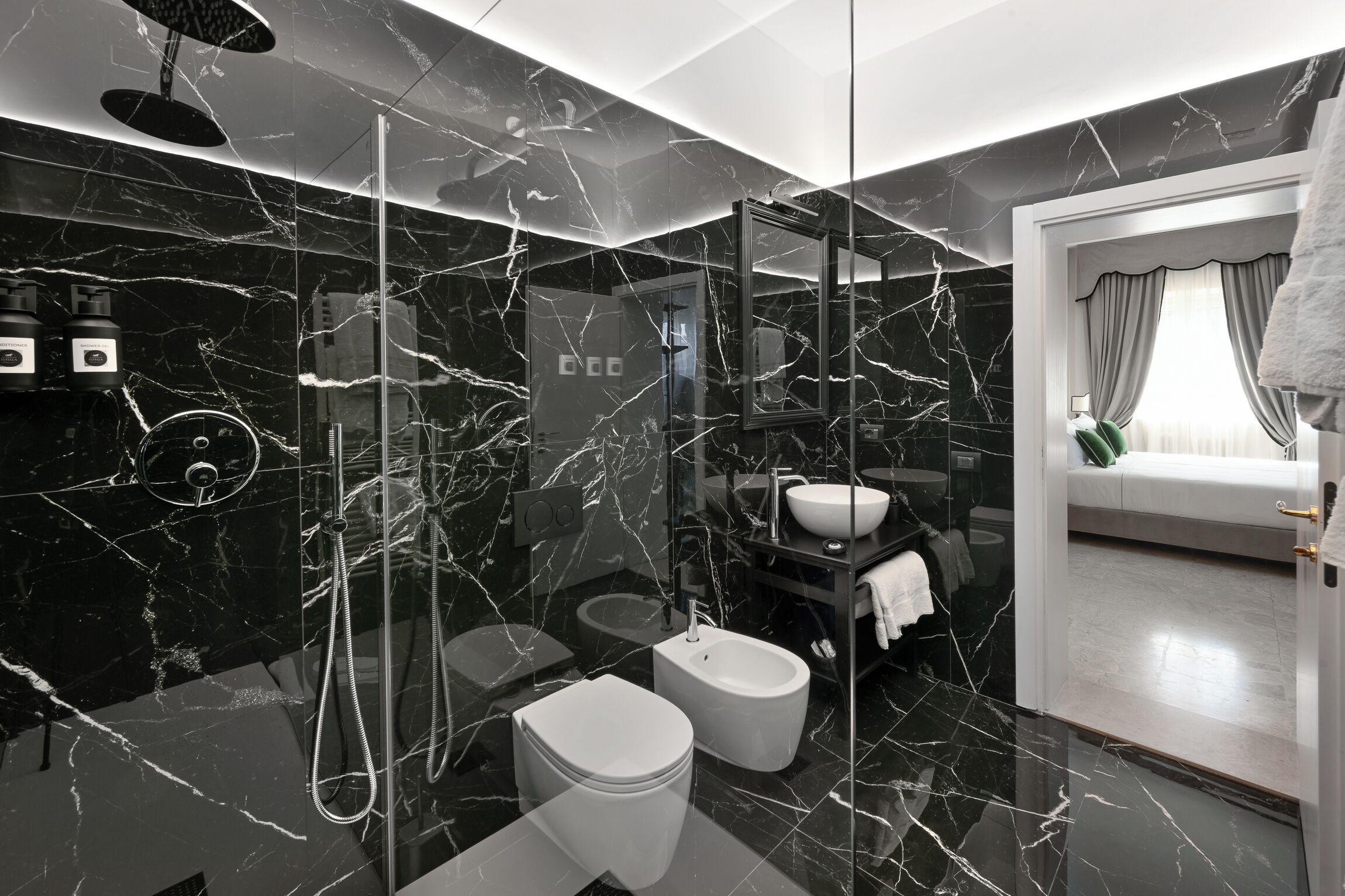 A modern bathroom with a glass shower enclosure, a bidet, a toilet, and a sink.