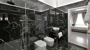 Un bagno moderno con box doccia in vetro, un bidet, un water e un lavandino.