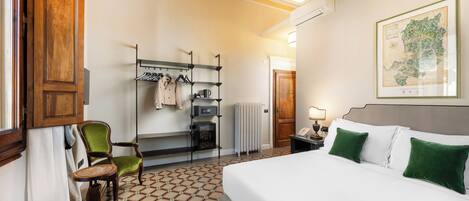 Une chambre d’hôtel avec un lit, une chaise, un bureau avec une bouilloire, un radiateur et une carte accrochée au mur.