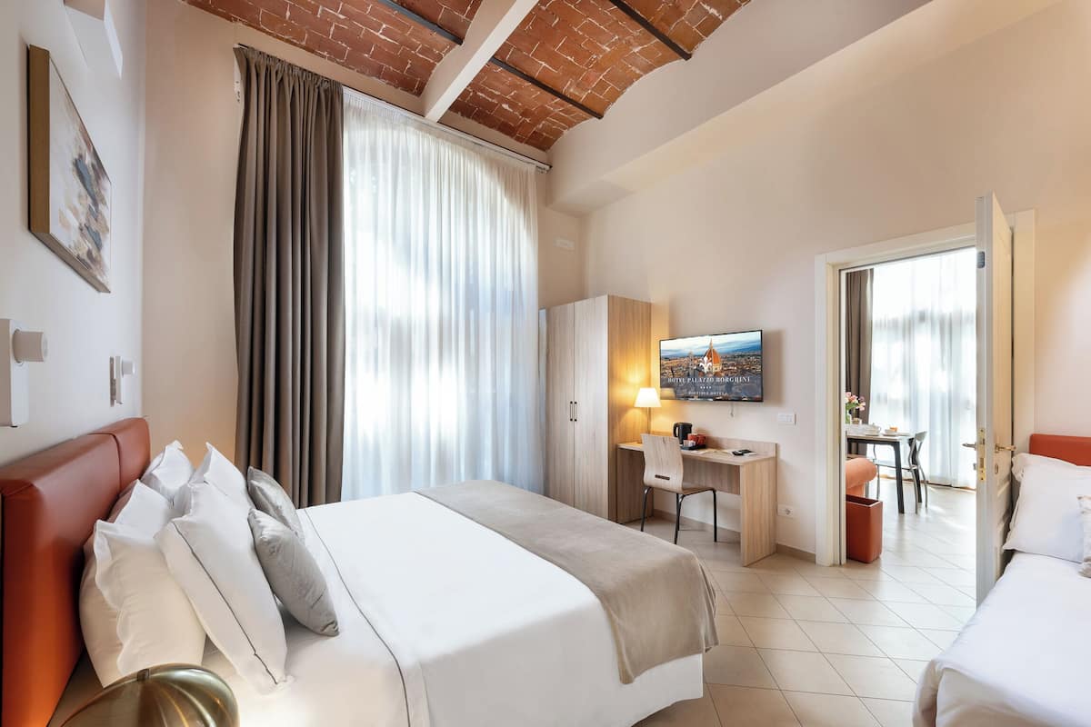 Ein Hotelzimmer mit Bett, Schreibtisch, Stuhl und Fernseher.