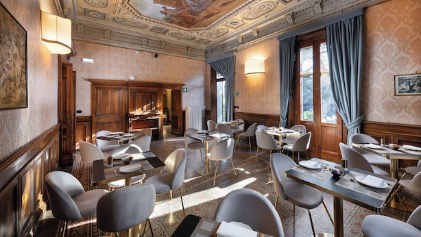 A dining area with tables and chairs, a ceiling mural, and patterned wallpaper. - Hotel Palazzo Borghini (Florence)