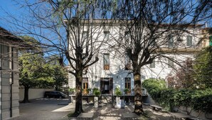 A courtyard with a building, trees, and outdoor seating. - Hotel Palazzo Borghini (Florence)
