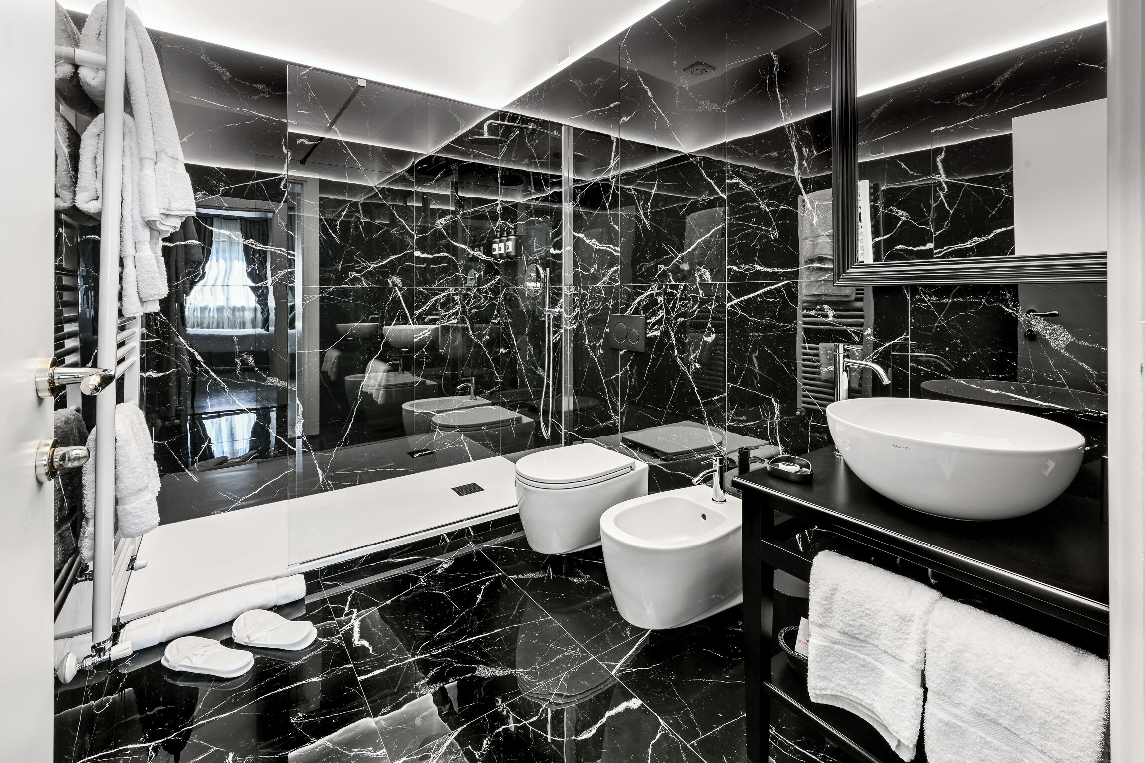 A modern bathroom with a large bathtub, a bidet, a sink, and a mirror.