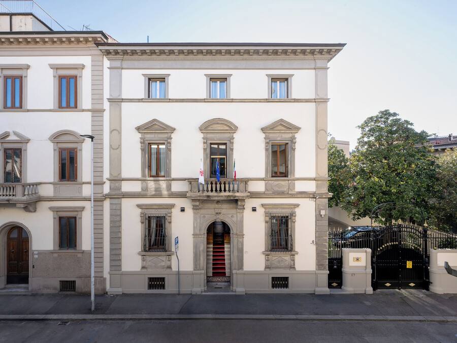 A classical building with a symmetrical facade, multiple windows, and a gated entrance.