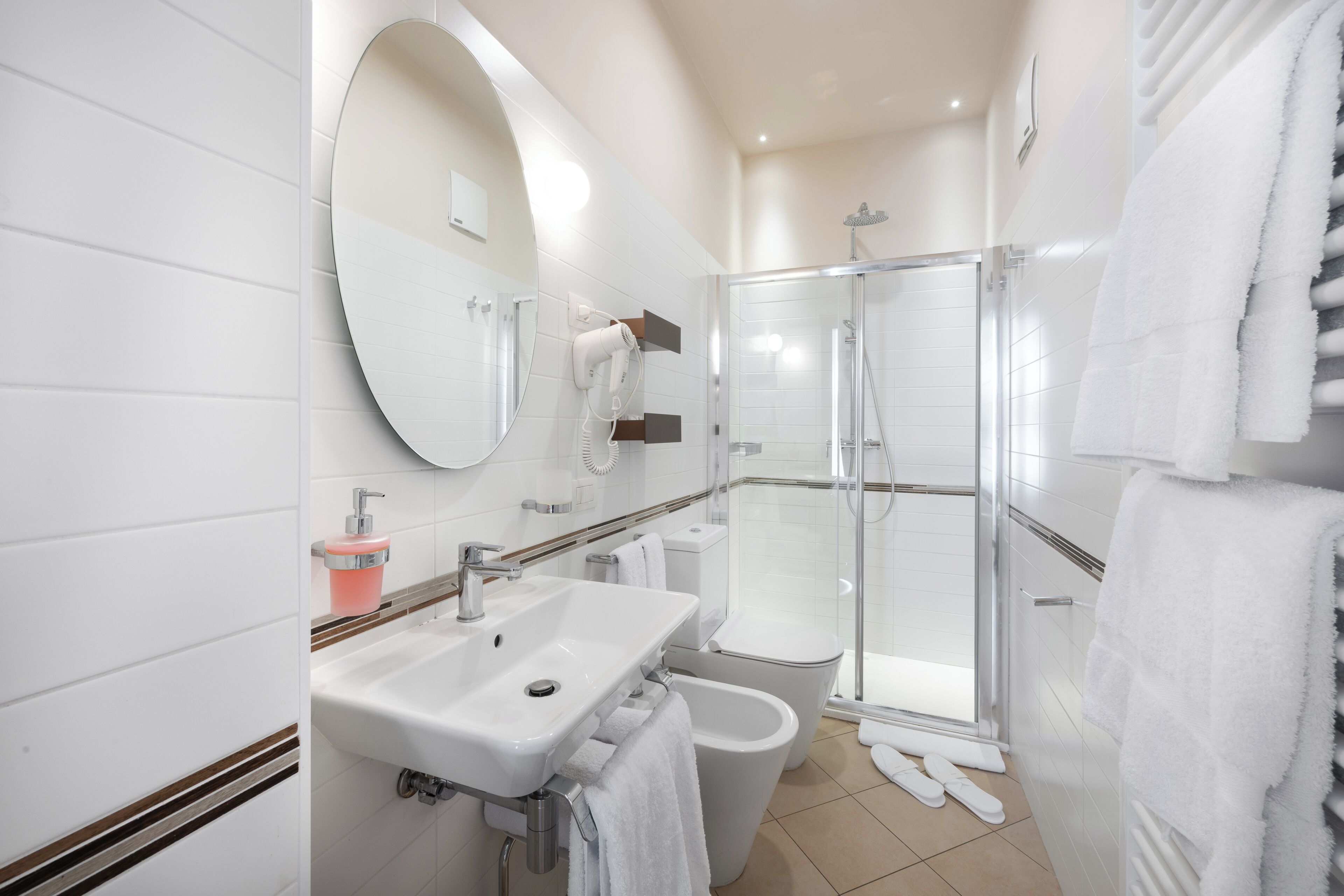 Et moderne badeværelse med vask, spejl, toilet og brusebad.