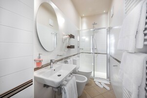 A modern bathroom with a sink, mirror, toilet, and shower.