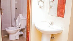 A bathroom with a toilet, sink, and a mirror. - Dandy Home, 2 BdRm, Estn Bypass Kamakis Greenspot (Ruiru)