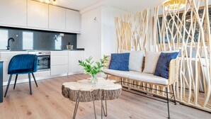 Eine moderne Küche mit weißen Schränken, einem eingebauten Ofen und einem Essbereich mit blauem Stuhl und rundem Holztisch.