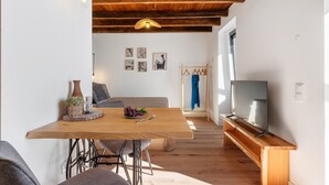 Un intérieur moderne avec une table à manger en bois, des chaises, un canapé, un téléviseur et des œuvres d’art accrochées au mur.