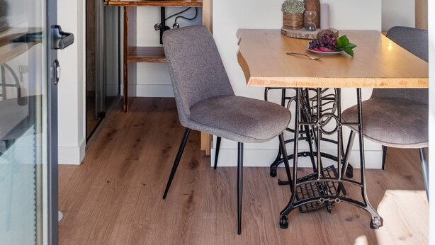 Une cuisine moderne avec un plafond en bois, un luminaire suspendu, un miroir rond et une table à manger avec deux chaises.