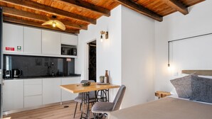 Une petite pièce comprenant un lit, une table en bois et un coin cuisine.