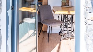 Une pièce dotée d’une porte en verre donnant sur un coin repas, d’un plafond en bois et d’un mur en pierre.