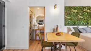 A modern kitchen with a wooden dining table, green chairs, and a breakfast setting. - Studio Apartment 'Ocean View Rock House  2' with Balcony and Wi-Fi (Caniço)