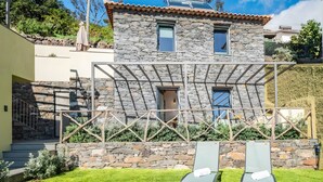 A stone house with a pergola, two lounge chairs, and a small table with a drink. - Studio Apartment 'Ocean View Rock House  2' with Balcony and Wi-Fi (Caniço)