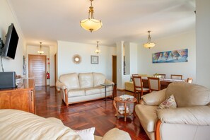 Un salon comprenant un canapé, une table basse et un téléviseur. Il y a également un coin repas avec une table et des chaises.