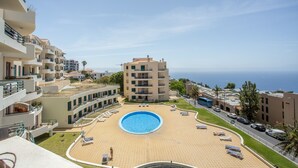 A residential building with a swimming pool, balconies, and a view of the sea. - Sunny Ocean View Apartment • Pool & Open Horizon (Caniço)