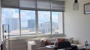 A modern living room with a sofa, dining table, and city view through large windows. - Cozy 1-bedroom apartment with AC in beautiful Atlanta (Atlanta)