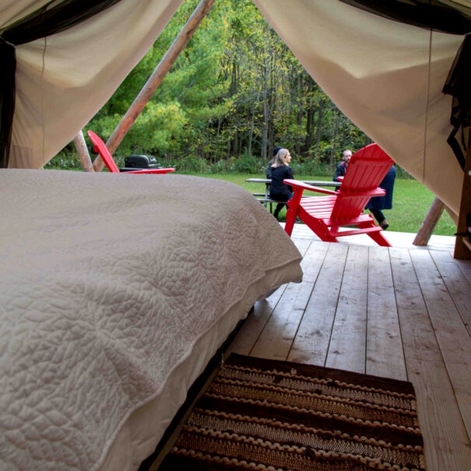 Eine Zeltoase mit Bett, roten Stühlen und einem Picknicktisch.