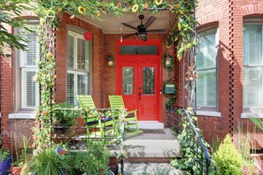 A red door with the number 222, a green chair, and a second green chair in front of a brick building. - Victorian Experience | Sleeps 6, Garden, 2‑Car Garage, Walk to Downtown (Savannah)