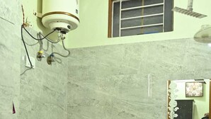 Une salle de bain équipée de toilettes, d’un lavabo, d’une douche et d’un chauffe-eau.