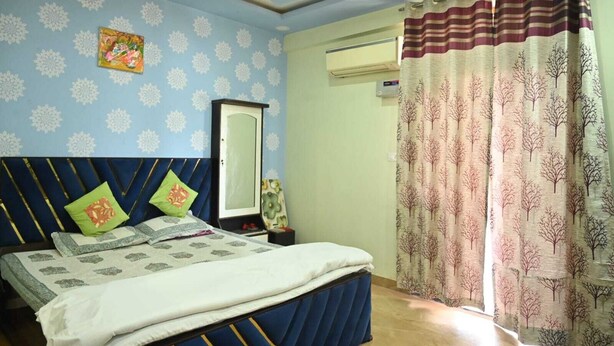Une chambre à coucher comprenant un lit, un ventilateur de plafond, un climatiseur fixé au mur et une fenêtre avec des rideaux.