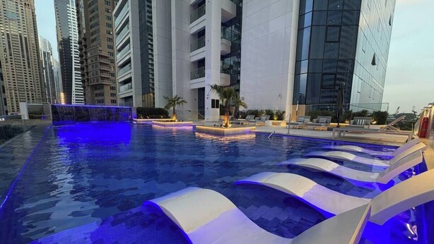 En swimmingpool med moderne design, omgivet af høje bygninger.