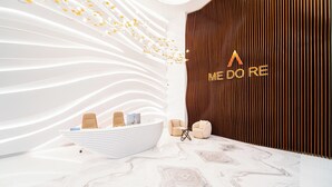 Moderne reception med hvid disk, to beige lænestole og en trævæg med logoet 'MEDORE'.