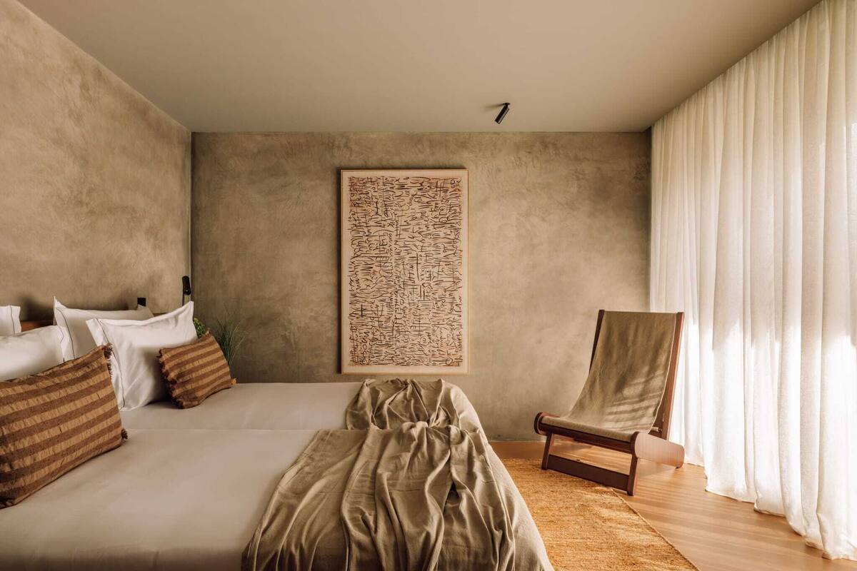 Ein modernes Schlafzimmer mit einem großen Bett, einem Sessel und einem Wandbild.