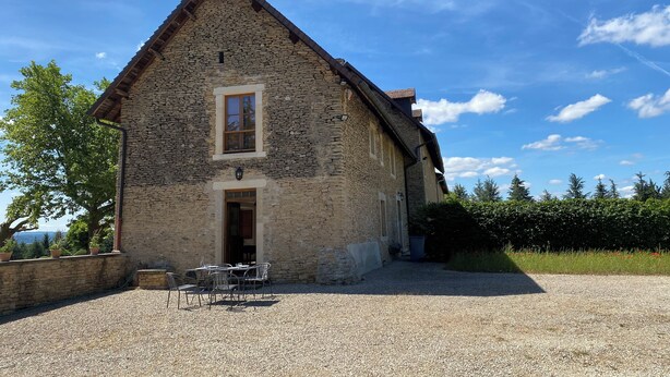Un bâtiment en pierre doté d’un toit à deux versants, d’une entrée centrale et d’une allée gravillonnée.
