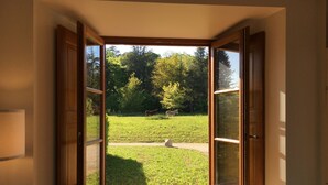 Une pièce dont la porte est ouverte et qui donne sur un espace extérieur verdoyant, avec des arbres et une clôture.