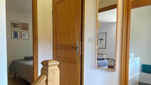 Un escalier en bois mène à une chambre à coucher qui contient un lit et une table de chevet.