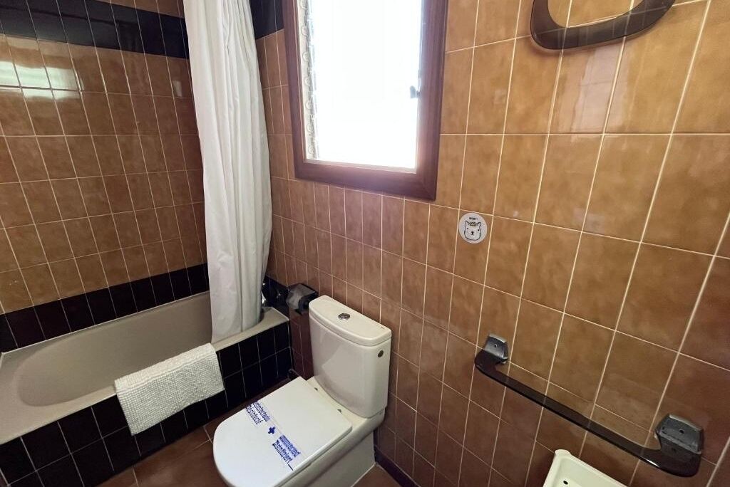 A bathroom with a toilet, a bathtub, and a window.