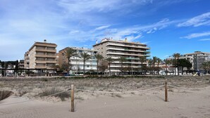 A beach with a volleyball net, sandy terrain, and multi-story buildings in the background. - Spacious 3-room apartment right on the beach. Rodes-71 (Calafell)