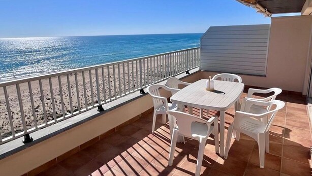 A balcony with a view of the sea, white plastic chairs, and a table. - Spacious 3-room apartment right on the beach. Rodes-71 (Calafell)