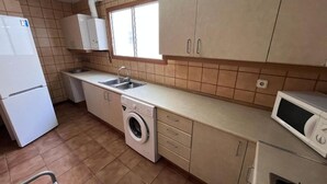 A compact kitchen with a washing machine, a microwave, and a refrigerator. - Spacious 3-room apartment right on the beach. Rodes-71 (Calafell)