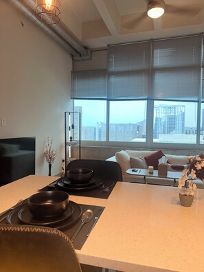 Ein modernes Wohnzimmer mit Essbereich, großen Fenstern und Blick auf die Stadt.