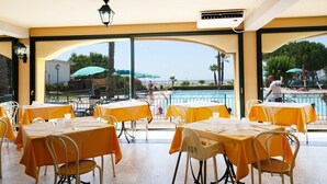 A restaurant with outdoor seating overlooking a pool and a view of the sea. - Marina del Marchese Resort (Botricello)