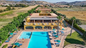 A hotel with a large pool, sun loungers, and a view of the surrounding landscape. - Marina del Marchese Resort (Botricello)