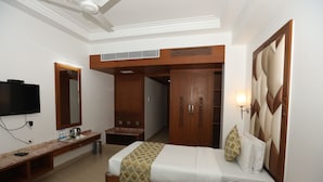 Una habitación de hotel con cama, televisión, escritorio, armario y baño.