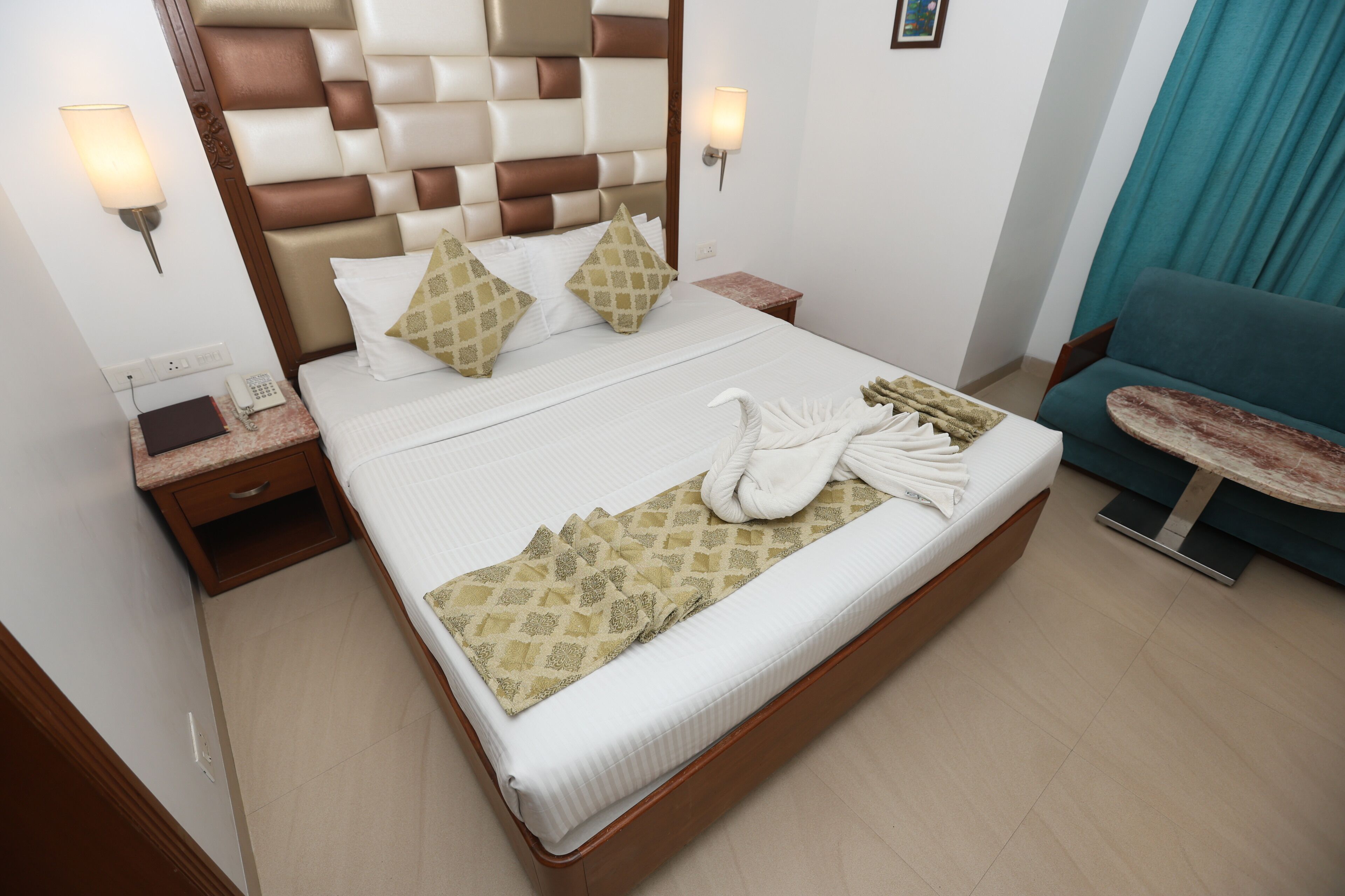A hotel room with a bed, a nightstand, a table, and a sofa.