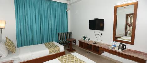 A hotel room with two beds, a TV, a mirror, a desk, and a chair.