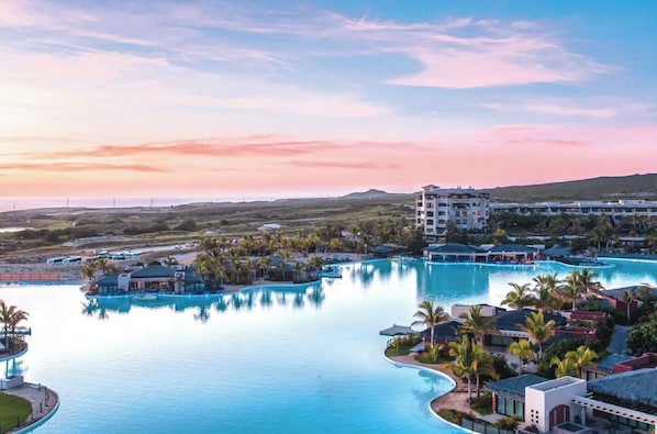 Ein Resort mit großem Pool, Palmen und einem Gebäude mit mehreren Balkonen.