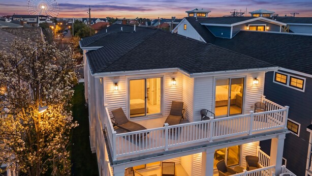 Een tweelaags huis met een balkon, grote ramen en een uitzicht op een reuzenrad in de verte.